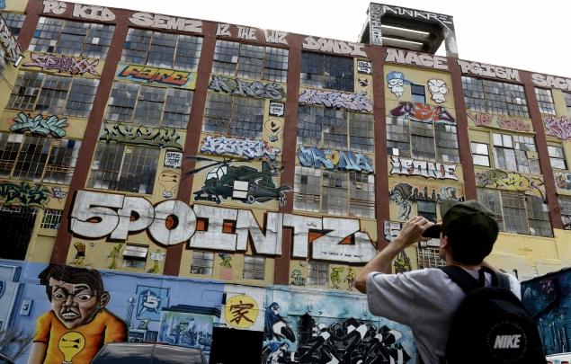 epa03827530 People look over the graffiti on a giant warehouse building complex, know as 5 Pointz, in Long Island City, New York, USA on 16 August 2013. The area has received acclaim as a graffiti mecca and has been used by graffiti artists since the early 1990s, but recently the property owner, Jerry Wolkoff, announced plans to raze the buildings to build high-rise residential buildings. Some community members are petitioning the government to consider the space a protected cultural landmark.  EPA/JUSTIN LANE